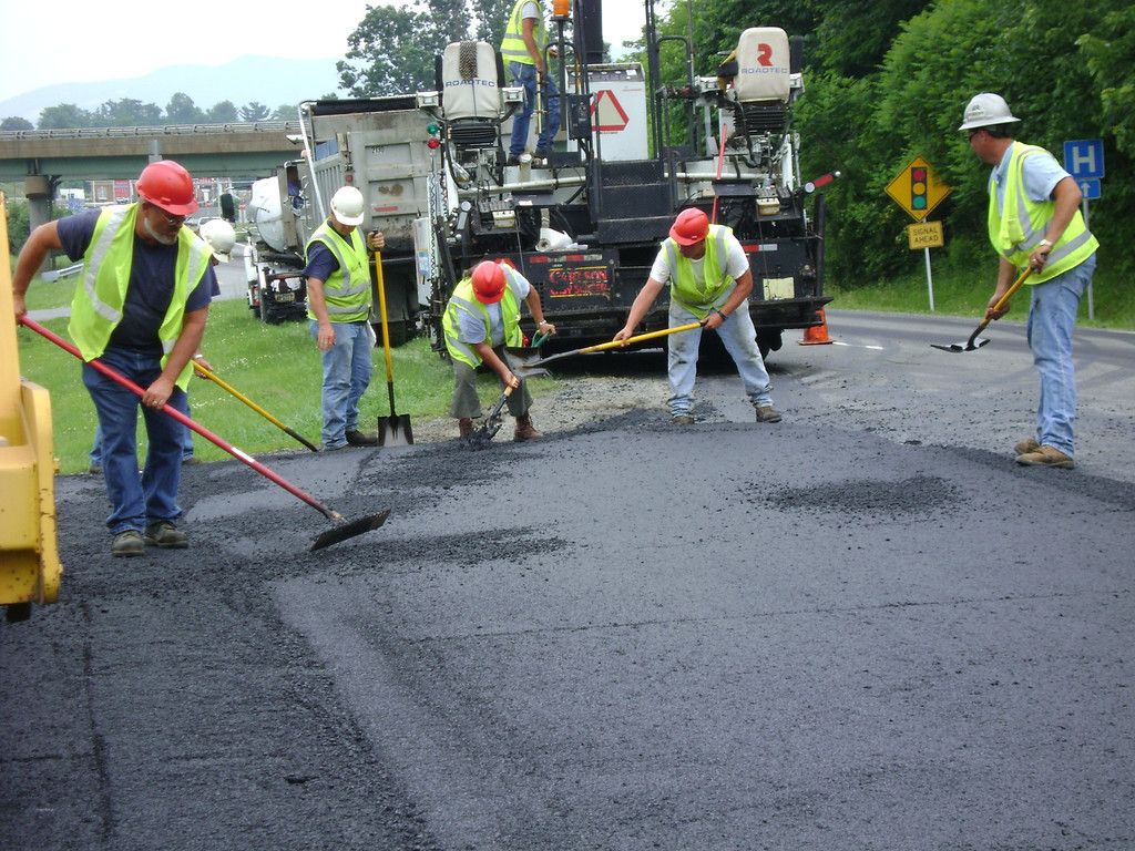 W-L paving crew in safety vests raking fresh asphalt